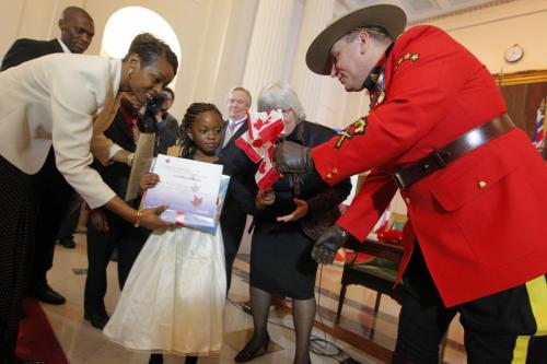 30 people became Canadian Citizens today at the Leg. The Nkana Bassi family of 4 were sworn in. Lea is the young girl getting a flag from the RCMP officer. Her brother Junior in behind her. Mother Carole on left. December 12, 2012  BORIS MINKEVICH / WINNIPEG FREE PRESS