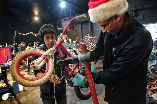 Seth Belmore (left), 12, and Dave Dorning the coordinator of the University of Winnipeg Students Association Bike Lab work on a bike together during the Cycle of Giving at the Atomic Centre on Logan Avenue. Dozens of mechanics have been working for the last twenty-four hours fixing up over 200 bicycles for Winnipeg children in need in the second annual event.  121216 December 16, 2012 Mike Deal / Winnipeg Free Press