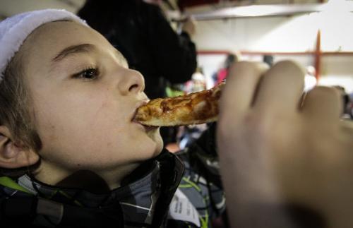 Mik Repko, 8, from Mulvey School devours his pizza while waiting for Santa to arrive. Around 150 kids from three Winnipeg School Division elementary schools, Strathcona, Mulvey and Dufferin, got to have lunch in the Winnipeg James Armstrong Richardson International Aiport's firehall where Santa just happened to be testing out the STARS helicopter. Fred Penner was on hand to perform some music too. 121217 - Monday, December 17, 2012 -  (MIKE DEAL / WINNIPEG FREE PRESS)