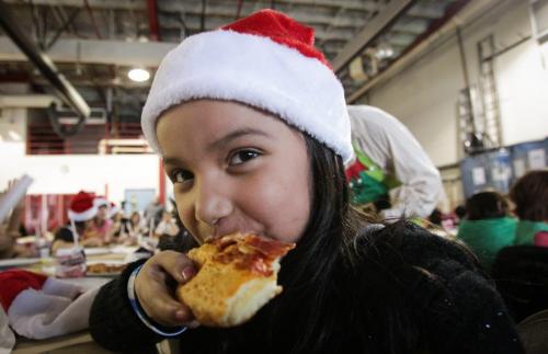 Rinelle Constant, 8, from Mulvey School enjoys her pizza while waiting for Santa to arrive. Around 150 kids from three Winnipeg School Division elementary schools, Strathcona, Mulvey and Dufferin, got to have lunch in the Winnipeg James Armstrong Richardson International Aiport's firehall where Santa just happened to be testing out the STARS helicopter. Fred Penner was on hand to perform some music too. 121217 - Monday, December 17, 2012 -  (MIKE DEAL / WINNIPEG FREE PRESS)