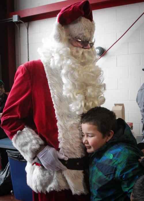 Tate Roulette, 6, from Strathcona School manages to get a special moment with Santa as everyone screams and chears as Santa (Doug Speirs) arrives after a flight on the STARS helicopter. Around 150 kids from three Winnipeg School Division elementary schools, Strathcona, Mulvey and Dufferin, got to have lunch in the Winnipeg James Armstrong Richardson International Aiport's firehall where Santa just happened to be testing out the STARS helicopter. Fred Penner was on hand to perform some music too. 121217 - Monday, December 17, 2012 -  (MIKE DEAL / WINNIPEG FREE PRESS)