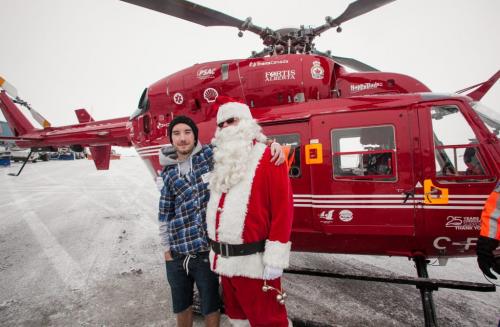 Santa Claus (Doug Speirs) posed with Sean Quigley, the You Tube sensation for Little Drummer Boy, in front of the STARS Air Ambulance after Santa's test flight Monday afternoon. The Winnipeg Airports Authority partnered with STARS to bring in 150 students to meet Santa and hear Quigley and Fred Penner perform. (Melissa Tait / Winnipeg Free Press)