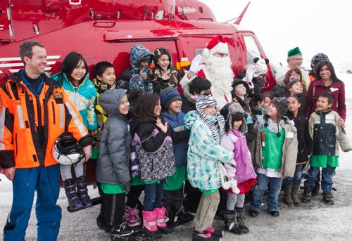 Students from Dufferin School pose with Santa Claus (Doug Speirs) and part of the STARS Air Ambulance team at the Winnipeg Airport firehall on Monday afternoon. 150 students were surprised by Santa's arrival on the STARS helicopter. (Melissa Tait / Winnipeg Free Press)