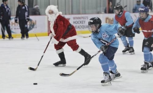 Rayden Tanner, 11, a grade six student from Ness Middle School, flies past Santa during the Winnipeg Jets Hockey Academy program at the MTS IcePlex Thursday afternoon. Santa is keeping in shape by getting some ice time with the WJHA in the days leading up to Christmas next week.  121220 December 20, 2012 Mike Deal / Winnipeg Free Press