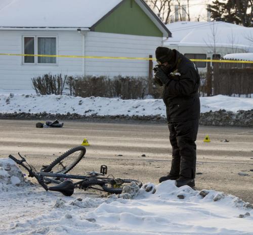 122312 Winnipeg - A Winnipeg Police Service Forensics officer takes photographs of a bicycle involved in a serious motor vehicle collision at the corner of Brewster Street and Regent Avenue Sunday morning. East and westbound Regent Avenue between Plessis Road and Brewster Street will be blocked for several hours Sunday as Police continue to investigate. DAVID LIPNOWSKI / WINNIPEG FREE PRESS