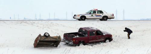An RCMP member documents the scene of a rollover on the Trans Canada West of Winnipeg Friday morning.  At least one was taken to hospital. Icy roads were an issue as warmer temps eased frost out of frozen roads. December 28, 2012 - (Phil Hossack / Winnipeg Free Press)