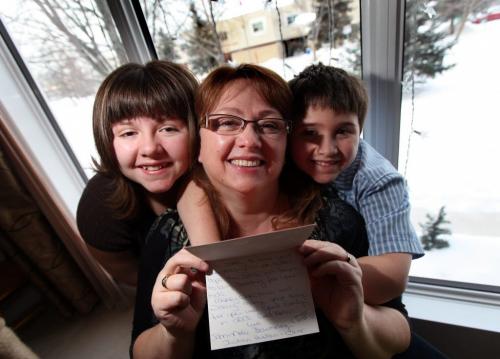 Trina Cimino, poses with her kids Kevin 8, and Sarah 11 holding a card from the School For the Deaf. Kids from the school across the road from her home helped out the family collecting donations after a holiday break in. Gabrielle's story. December 28, 2012 - (Phil Hossack / Winnipeg Free Press)