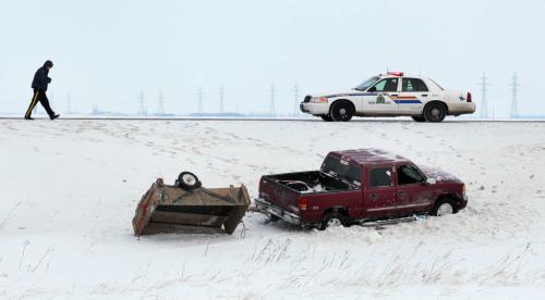 An RCMP member documents the scene of a rollover on the Trans Canada West of Winnipeg Friday morning.  At least one was taken to hospital. Icy roads were an issue as warmer temps eased frost out of frozen roads. December 28, 2012 - (Phil Hossack / Winnipeg Free Press)