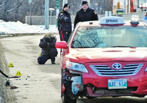 Winnipeg Police Service officers document the scene of a vehicle accident involving a taxi on North bound Osborne Street just north of the Osborne Street bridge.  Indications are it could be that a pedestrian was involved.  130101 January 01, 2013 Mike Deal / Winnipeg Free Press