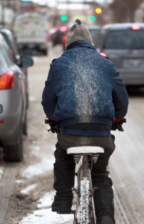 Messy drive- A cyclist has a giant mud track on his back from wet muddy snow while driving down King St in rush hour traffic - Standup Photo- January 08, 2013   (JOE BRYKSA / WINNIPEG FREE PRESS)