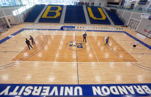 Brandon Sun Visitors to the Brandon University Healthy Living Centre make their rounds of the second-floor jogging track  as Bobcat players practuce a few shots during Saturday's open house. (Bruce Bumstead/Brandon Sun)