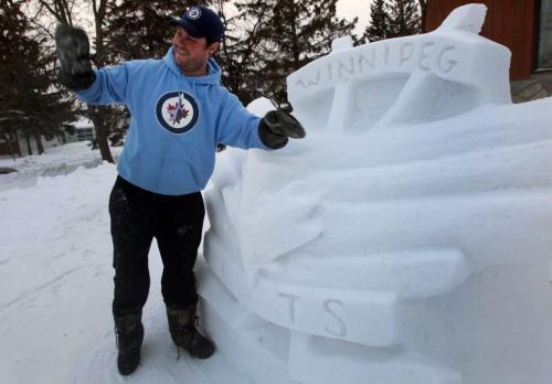 Jets Sculpture- 34 yr old sculptor Cameron Chouinard waves to honking cars as he cleans snow off his Jets sculputure he made in front of his home on Autumnwood Dr-Standup photo- January 18, 2013   (JOE BRYKSA / WINNIPEG FREE PRESS)