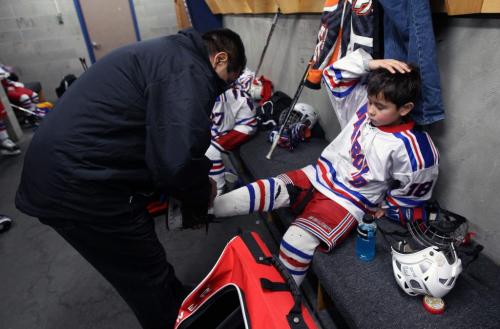 Warroad, Minnesota- 9 year old Daimon Gardner, right, gets his skate taken off by Dad and coach Vince Gardner- He missed the third period because of his bruised foot  His team was taking on the team from Hallock, Minnesota-See Randy Turners hockey FYI  story- January 29, 2013   (JOE BRYKSA / WINNIPEG FREE PRESS)