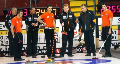 Steen Sigurdsonn points his broom while consulting with his father  and coach Barrie Wednesday afternoon at the Safeway Championship in Neepawa..his squad in orange awaits the decision left to right, lead Nick Curtis, 3rd Riley Smith and Ian McMillan far right....THey took on the local favorite Kelly Robertson of Neepawa. See Wiecek's story. February 6, 2013 - (Phil Hossack / Winnipeg Free Press)