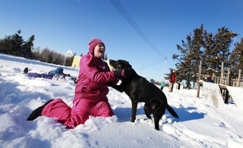 Celina Summerfeld in grade 4.hugs the school dog "Dakota" while playing outside at recess at Reynolds School. Reynolds School in the RM of Reynolds  a hour and a half east of Winnipeg has only 9 kids attending ithe school due to low enrollment. Students head outside for recess where they make snow angles, play with the dog, go sliding and dig snow tunnels. See Nick Martin's story. Jan 16 2013, Ruth Bonneville  (Ruth Bonneville /  Winnipeg Free Press)