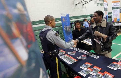 RCMP Const. Ron Bumbry speaks with Kayode Oderemi, one of hundreds of people who attended the Afro-Caribbean Job Fair at Elmwood High School, February 9, 2013. (TREVOR HAGAN/WINNIPEG FREE PRESS)