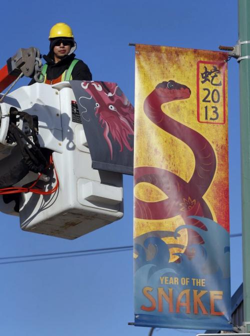STDUP- Chris Vidallon of Mytec Industries raises one of 35 new way finding banners as part of a Wpg BIZ 's annual Chinatown Banner Competition , 18 are new banners  along with 17  new district banners that will help define the  boundaries of Chinatown Äì pic taken at Princess St at Logan  KEN GIGLIOTTI / FEB 12 2013 / WINNIPEG FREE PRESS