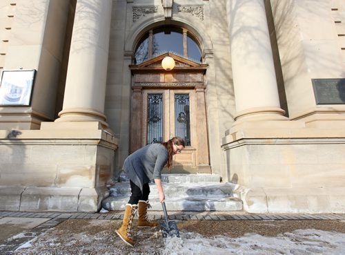 Brandon Sun 13022013 Becky Farguson with the Brandon Chamber of Commerce chips away ice in front of the Rosser Ave. building on a warm Wednesday afternoon. (Tim Smith/Brandon Sun)