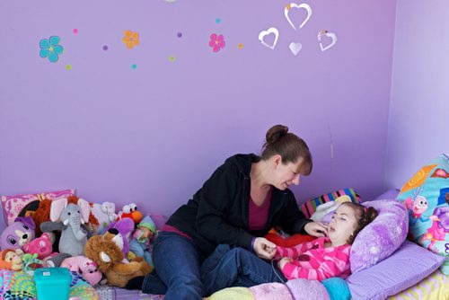 Brandon Sun 13022013 Rhonda Towler visits with her five-year-old daughter Emma, who has Ohtahara syndrome, a rare progressive epileptic encephalopathy, in the living room of their home on Friday. Towler is frustrated over the lack of support her daughter has received from Childrens disABILITY Services. (Tim Smith/Brandon Sun) ***double check that cutline matches with story please***