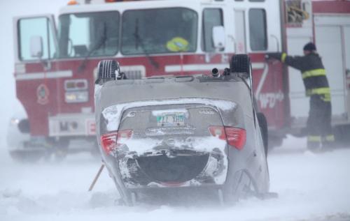 Police and paramedics attend to a vehicle on its roof on the North Perimeter near Brookside Blvd. Blowing snow caused poor visibility on the Perimeter and many vehicles wound up in the ditch, February 18, 2013. (TREVOR HAGAN/WINNIPEG FREE
