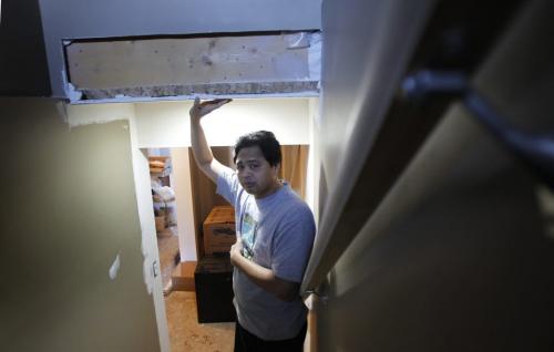 Arnel Mercado lives in a Pritchard Avenue home (695 Pritchard) that was built with falsified engineering seals, which the city is now investigating. Mercado said the city did not discover the problem until he applied for a permit to renovate his basement in November. Arnel is in the stairway to the basement where the Inspector found the headroom for the  stairs too low to meet code. He is holding a support beam. Jen Skerritt  story    (WAYNE GLOWACKI/WINNIPEG FREE PRESS) Feb. 19 2013