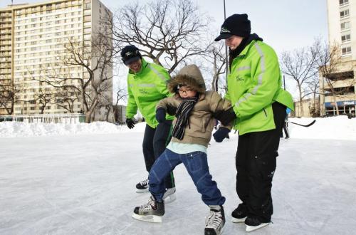 Jairus Santos, 8, gets some help from Crisanto Landicho and Laura Ramsay from the West End Biz as he skates for the first time.  The WPS, Central Neighbourhoods Development Corp, and West End Biz held a learn-to-skate event for inner city youth and families at Central Park. 130220 February 20, 2013 Mike Deal / Winnipeg Free Press
