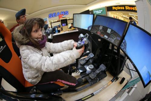 Emma Moore, 5, tries her hand at a flight simulator as Cadet, Joshua Woodland, 18, from the 176 Boeing of the Royal Canadian Air Cadet Squadron, looks on, in Kildonan Place Mall, Saturday, February 23, 2013. (TREVOR HAGAN/WINNIPEG FREE PRESS)