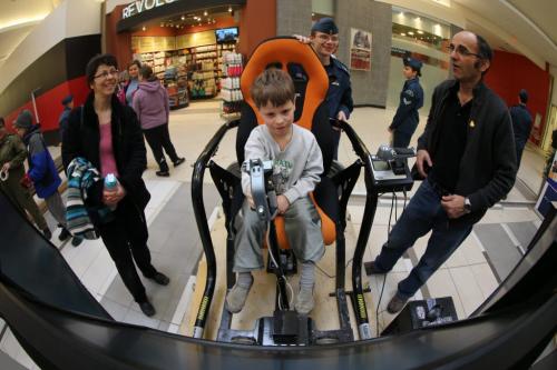 Sopie Ramer watches as her son Benjamin, 6, tries out a flight simulator at Kildonan Place Mall. Cadet, Josua Woodland, 18, of the 176 Boeing of the Royal Canadian Air Cadet Squadron, and Vern Toews, Co-Sponsor Committee Chair give instructions, Saturday, February 23, 2013. (TREVOR HAGAN/WINNIPEG FREE PRESS)