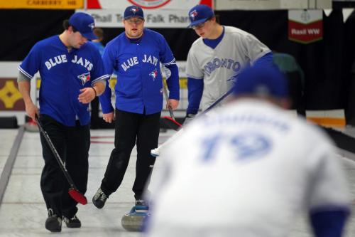 Carberry's Scott Witherspon (center) keeps his sweeper's Mike Reykdal (left) and Warren Birch (right) on track at a community bonspiel held in Carberry annually. His team uniform honoring another rural passtime, baseball. Featuring over a hundred teams, the spiel is a success story in the rural curling world. Feb 21, 2013 - (Phil Hossack / Winnipeg Free Press)