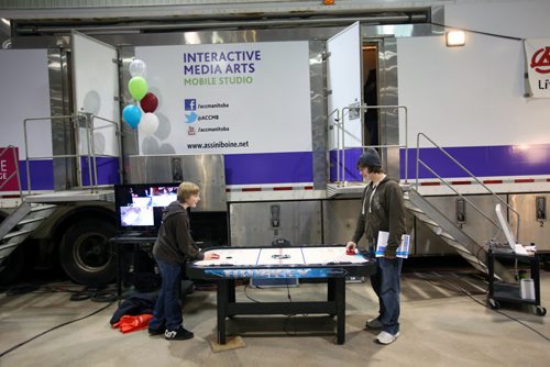 Brandon Sun 05032013 Vincent Massey High School students Ryan McKean and Matthew Elton play air hockey in front of Assiniboine Community College's Interactive Media Arts booth during the 28th Annual Brandon Career Symposium at the Keystone Centre on Tuesday. (Tim Smith/Brandon Sun)