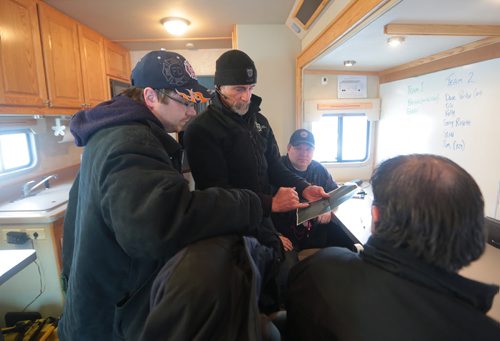 Brandon Sun SARMAN K-9 handler Mike Gilbertson, centre, points out on a satellite image were crash victim, played by GSAR volunteer Sheldon Gould, left, inside the mobile command unit of the Office of the Fire Commissioner. (Bruce Bumstead/Brandon Sun)