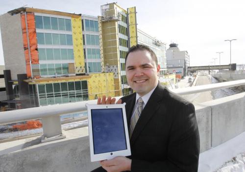 Neil Fishman General Manager, of The Grand Winnipeg Airport Hotel by Lakeview holds an iPad by the hotel under construction at left . The Grand Hotel (when it opens in July) will have an iPad in every room that will function as the service contact for guests for everything from room service to a digital source for all the info on the hotel and the area that guests typically find in paper form in every room. It will be the first hotel in the city with this iPad innovation. Martin Cash story.   WAYNE GLOWACKI/ WINNIPEG FREE PRESS) WINNIPEG FREE PRESS  March 7 2013