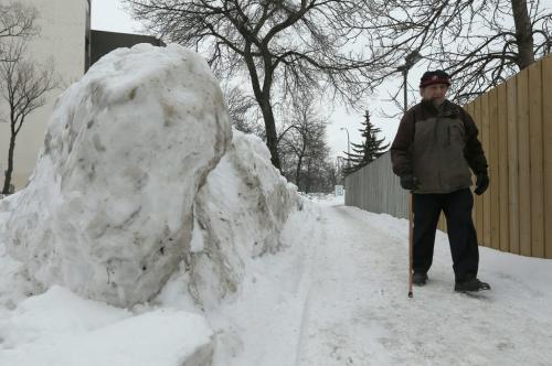 A pedestrian walks on the sidewalk behind a five-foot tall snowbank left by snowplows along Simcoe Street in the West End neighbourhood of Winnipeg, on on Sat., March 9, 2013. Photo by Jason Halstead/Winnipeg Free Press **SUBJECT DIDN'T WISH TO GIVE NAME, BUT WAS OK BEING PHOTOGRAPHED FOR PAPER**