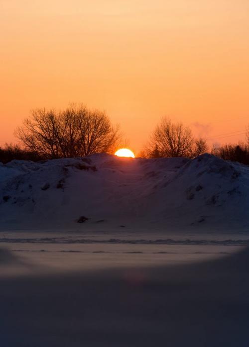 Wednesday morning's sunrise over piles of snow outside Pan Am pool. (Melissa Tait / Winnipeg Free Press)