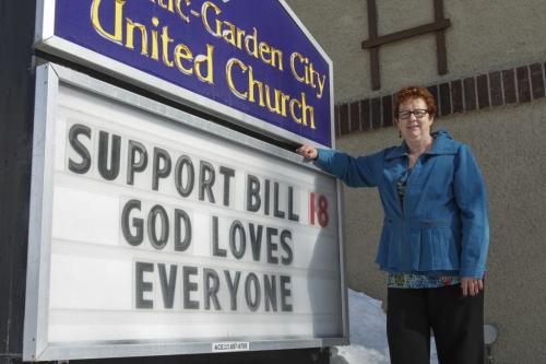 Reverend Mary Best stands outside the Atlantic-Garden City United Church at Arlington St. on Thursday, March 14, 2013 next to a sign that promotes support of Bill 18. The sign states that "God loves everyone," in the hopes of inducing an anti-bullying sentiment. March 14, 2013. (STORY BY BRUCE OWEN) (JESSICA BURTNICK/WINNIPEG FREE PRESS)