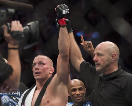 Georges St-Pierre from Canada, left, has his arm raised by an official following his UFC 158 welterweight title defence against Nick Diaz from the United States in Montreal, Saturday, March 16, 2013. THE CANADIAN PRESS/Graham Hughes.