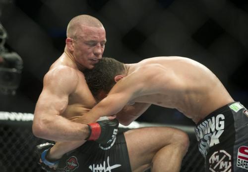 Georges St-Pierre, left, from Canada lands a knee to the body of  Nick Diaz from the United States during their UFC 158 welterweight title fight in Montreal, Saturday, March 16, 2013. THE CANADIAN PRESS/Graham Hughes.