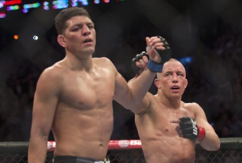 Georges St-Pierre, right, from Canada raises the arm of Nick Diaz from the United States following their UFC 158 welterweight title fight in Montreal, Saturday, March 16, 2013. THE CANADIAN PRESS/Graham Hughes.