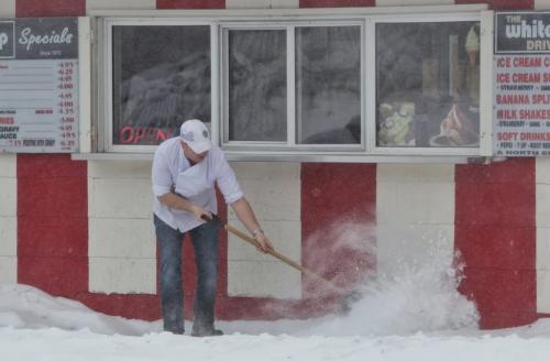 Mike Rogers a chef at the White Top Drive-In clears out the sidewalk as high winds toss the snow back at him Monday morning.  130318 March 18, 2013 Mike Deal / Winnipeg Free Press