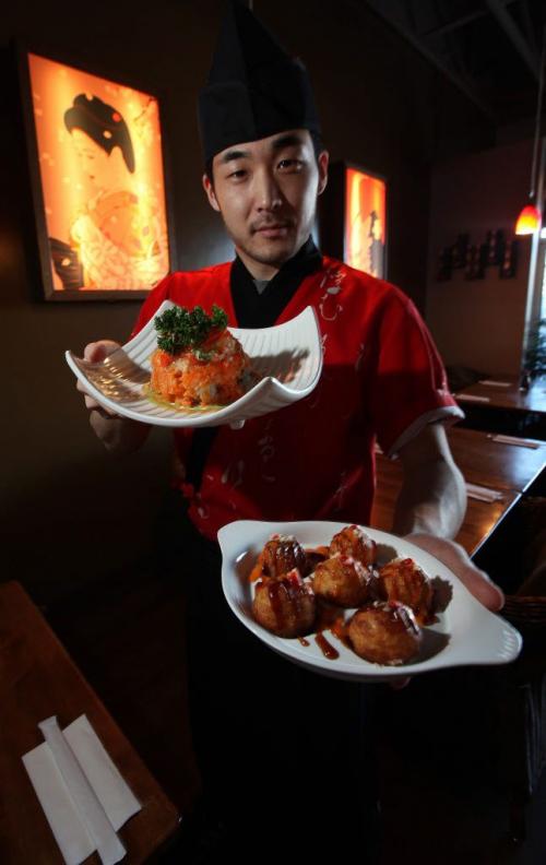 Sushi Chef Woo Can holds up Volcano roll (Top)  and Takoyaki dumpling, two of the dishes Marion Warhaft review in her piece on Sushi ai. A Japanese Bistro on St Annes Rd. See her story. March 18, 2013 - (Phil Hossack / Winipeg Free Press)