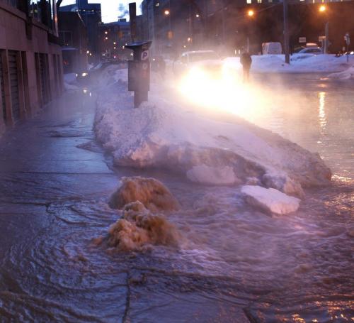 A motorist on Bannatyne. Ave at Dagmar St. Thursday morning looks at the scene of a large water main break flooding the street. This sidewalk was in front of 365 Bannatyne Ave where some of the water was gushing up. (Wayne Glowacki Winnipeg Free Press) Winnipeg Free Press March 21 2013