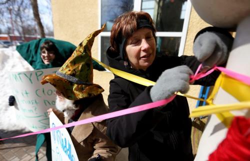 Leslee Silverman, who was recently let go, after serving 30 years as Manitoba Theatre for Young PeopleÄôs founding artistic director, wrapping ribbon around the exterior of the MTYP, Saturday, March 23, 2013. (TREVOR HAGAN/WINNIPEG FREE PRESS)