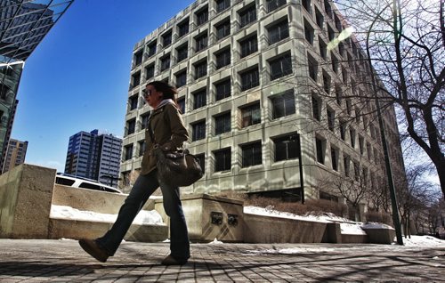 A pedestrian walks along Hargrave Street downtown past a building illuminated by the noonday sun reflecting off of the HSBC Bank Canada building.  130325 March 25, 2013 Mike Deal / Winnipeg Free Press