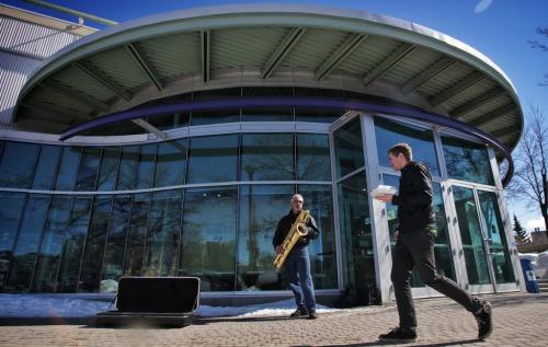 John Chesley plays his baritone sax outside at The Forks as pedestrians walk by.  130325 March 25, 2013 Mike Deal / Winnipeg Free Press