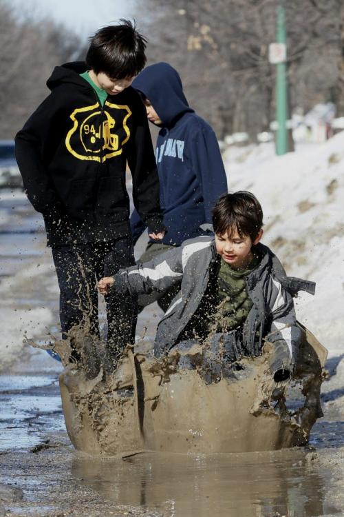 March 25, 2013 - 130325 - Brothers (LtoR) Dakota (10), Carson (8), and Brandon (6) Harper have some fun in a puddle in the Robertson area of Winnipeg Monday, March 25, 2013. John Woods / Winnipeg Free Press