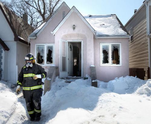 A fire investigator makes his way out of a home at 800 Mountain ave. Officials remained at the scene of the suspicious fire hours after the flames were doused. See story. March 26, 2013 - (Phil Hossack / Winnipeg Free Press)