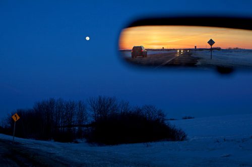 Brandon Sun 26032013 The rearview mirror reflects sunset to the west along Highway 10 near Minnedosa as an almost full moon rises to the east on Monday evening. (Tim Smith/Brandon Sun)