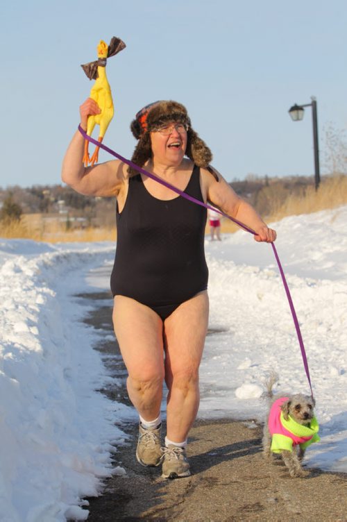 Brandon Sun 26032013 Kim Bright of the Brandon granny defies winter video series, jogs along the path at the Riverbank Discovery Centre on Tuesday evening while filming the final instalment of her video series with a group of supporters. Approximately a dozen supporters donned bathing suits and joined Bright for the jog.  (Tim Smith/Brandon Sun)