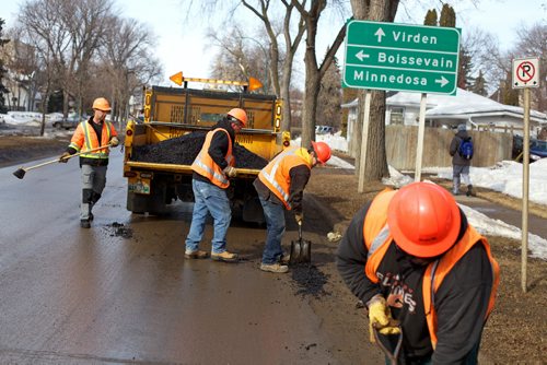 Brandon Sun 03042013 Workers with Manitoba Infrastructure and Transportation patch potholes along Victoria Avenue with cold mix on Wednesday morning. Two crews were kept busy patching the many potholes that line the avenue. (Tim Smith/Brandon Sun)