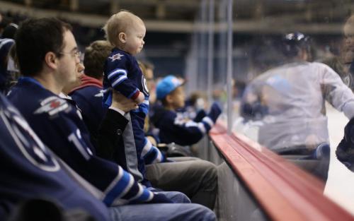 Derek Stein, his wife Leanne, and their son, Riley, 1, watching the Winnipeg Jets' practice at MTS Centre. About 3000 fans from the ticket waiting list were invited to the special event, Sunday, April 14, 2013. (TREVOR HAGAN/WINNIPEG FREE PRESS)